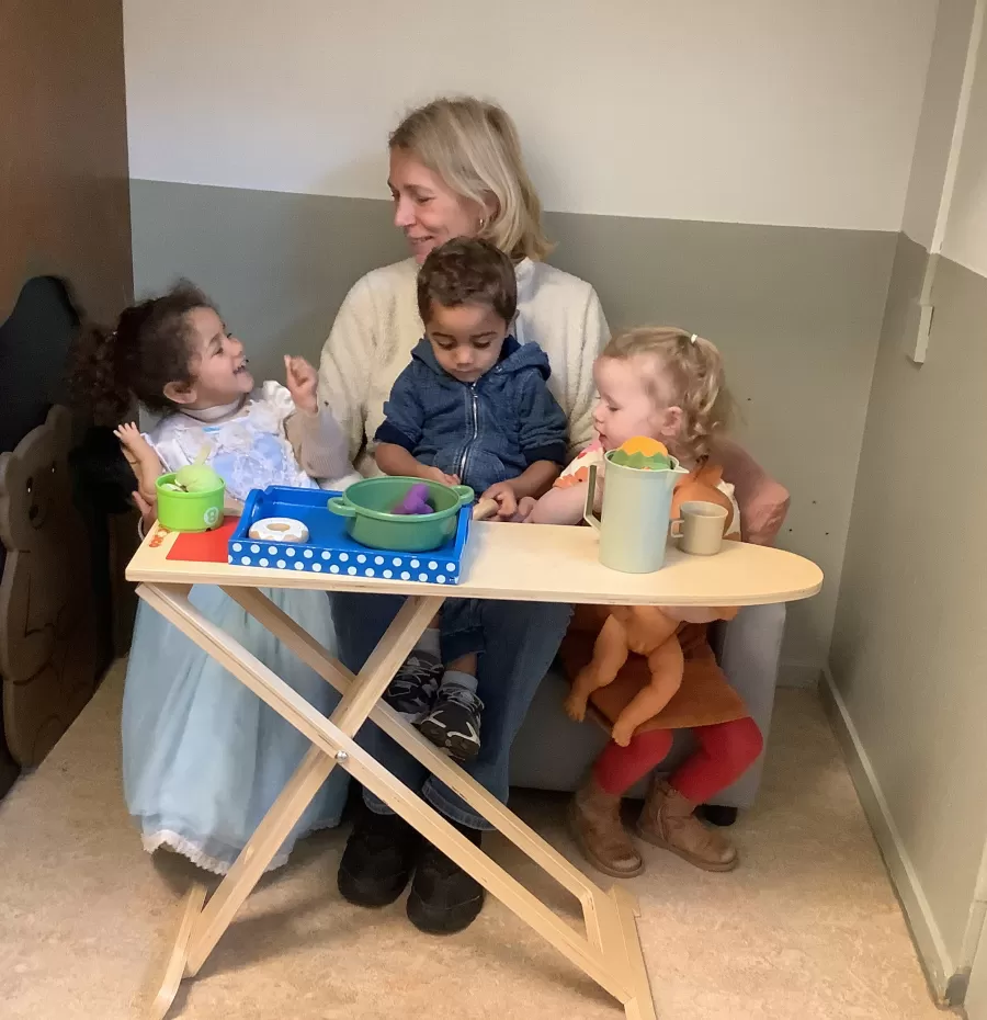 Ilonka zit met peuters in de poppenhoek
